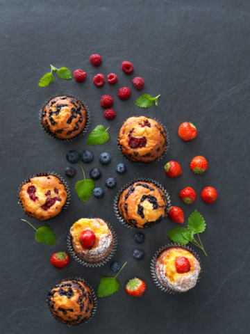 Muffins on a black table with berries